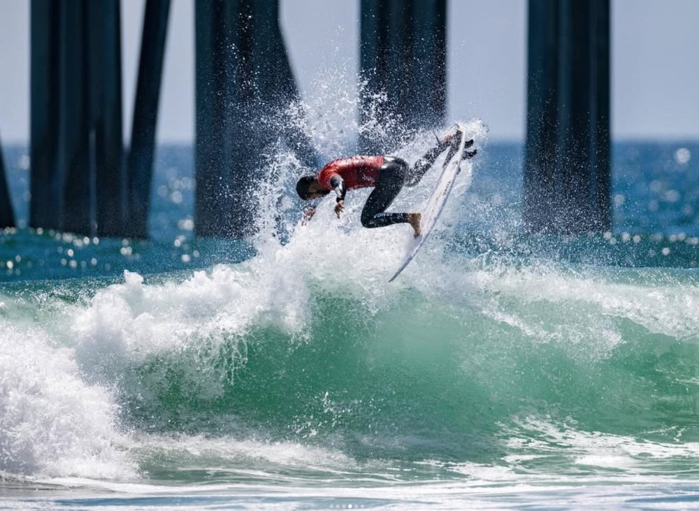 Surfer edgroggia riding a wave in front of a pier