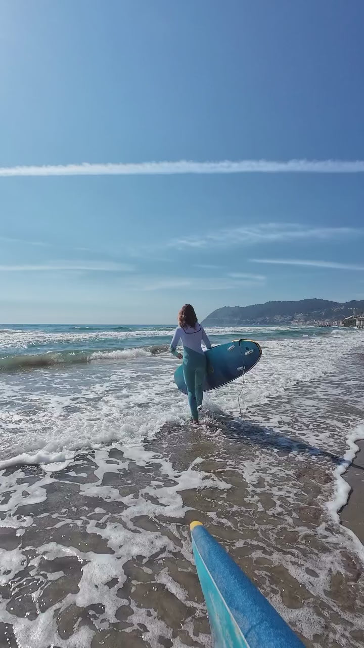 Load video: woman surfing in white and blue wetsuit